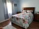 Cozy bedroom featuring light blue walls, a floral bedspread, and natural light from the window at 13031 W Surrey Ave, El Mirage, AZ 85335