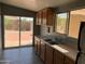 Bright kitchen with double sink, wood cabinets, and sliding door access to backyard at 13031 W Surrey Ave, El Mirage, AZ 85335