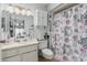 Well-lit bathroom featuring a shower-tub combination with floral shower curtain, along with storage space at 13821 N Thunderbird Blvd, Sun City, AZ 85351