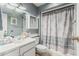 Clean bathroom with white vanity, mirror, and a shower-tub combination with a patterned shower curtain at 13821 N Thunderbird Blvd, Sun City, AZ 85351