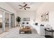 Bright living room with modern furniture, ceiling fan, light wood floors, and sliding glass doors to outdoor space at 13821 N Thunderbird Blvd, Sun City, AZ 85351