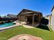 Charming backyard featuring a pool, covered patio with outdoor dining, and artificial turf for easy maintenance at 14282 W Indianola Ave, Goodyear, AZ 85395