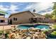 Private backyard oasis featuring a sparkling pool, gazebo, and unique rock waterfall feature with lush plants at 14282 W Indianola Ave, Goodyear, AZ 85395