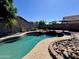 Inviting backyard pool featuring rock accents, lush landscaping, and ample space for relaxing under the sun at 14282 W Indianola Ave, Goodyear, AZ 85395