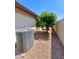 Side yard view with an orange tree, gravel landscaping, and an air conditioning unit at 1516 E Azalea Dr, Gilbert, AZ 85298
