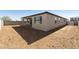 View of the back of the house with covered patio and a large dirt backyard at 15656 W Mercer Ln, Surprise, AZ 85379