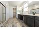 Spacious primary bathroom with double vanity, dark cabinets, walk-in shower, and tile flooring at 15656 W Mercer Ln, Surprise, AZ 85379