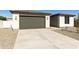View of the home's exterior displaying its neutral color palette, gravel landscaping, and spacious driveway at 15656 W Mercer Ln, Surprise, AZ 85379
