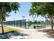 Enclosed pickleball court surrounded by mature trees, offering a shady and private playing experience at 15656 W Mercer Ln, Surprise, AZ 85379