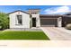 Charming single-story home with manicured landscaping, stone accents, and a brick-paved driveway leading to a two-car garage at 17168 W Mountainair St, Surprise, AZ 85388