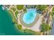Aerial view of a lagoon-style pool with sandy beach, lush landscaping, and lakeside access at 1835 E Marquette Dr, Gilbert, AZ 85234
