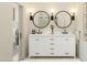 Bright bathroom featuring double sinks, white cabinets, round mirrors, and modern light fixtures at 20326 W Roma Ave, Buckeye, AZ 85396