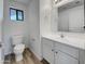 Bathroom features a toilet, single sink vanity with white cabinets and wood-look floors at 21334 E Lords Ct, Queen Creek, AZ 85142