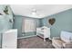 Bedroom painted in dark teal featuring a crib, chair, carpet, and shelving at 21716 S 225Th Way, Queen Creek, AZ 85142