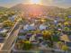 Stunning aerial view of a Scottsdale neighborhood with lush landscaping, a pool, and mountain views at sunset at 2712 E Mountain View Rd, Phoenix, AZ 85028