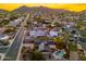 Scottsdale neighborhood aerial view featuring mountain views at sunset and a home with mature trees and a private pool at 2712 E Mountain View Rd, Phoenix, AZ 85028