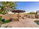 Inviting backyard with built-in fireplace, grill, and desert landscaping with a large umbrella providing shade at 2712 E Mountain View Rd, Phoenix, AZ 85028