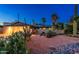 Charming desert home with low wall, desert landscaping including cacti, gravel, rock and mature palm trees at twilight at 2712 E Mountain View Rd, Phoenix, AZ 85028