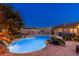 Inviting pool area at twilight with lush landscaping, built-in fireplace, and ambient lighting, creating a relaxing outdoor oasis at 2712 E Mountain View Rd, Phoenix, AZ 85028