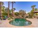 Backyard pool with rock waterfall feature, lush landscaping, and several palm trees at 2712 E Mountain View Rd, Phoenix, AZ 85028