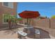 Shot of the backyard patio with stone table, bench seating, and orange sun umbrella at 2784 E Honeysuckle Pl, Chandler, AZ 85286