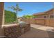 Covered outdoor kitchen with stainless steel grill and stone finish, yard, and green shrubbery at 2784 E Honeysuckle Pl, Chandler, AZ 85286