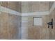 Close up on a tile shower with brown tile, stone accent, and recessed shampoo holder at 2784 E Honeysuckle Pl, Chandler, AZ 85286