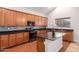Kitchen with wood cabinets, a central island with a dark countertop, and black appliances at 4626 N 111Th Ln, Phoenix, AZ 85037