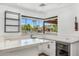 This wet bar features marble counters, wine fridge, sink, backyard waterfall views, and open shelving at 5838 E Berneil Ln, Paradise Valley, AZ 85253