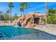 Luxury pool with rock waterfall and slide, complemented by palm trees and blue sky at 5838 E Berneil Ln, Paradise Valley, AZ 85253