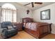 Well-lit bedroom featuring a ceiling fan, a dark wood bed, and a comfortable black chair with a pillow at 5839 W Ironwood Dr, Glendale, AZ 85302