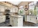 Bright kitchen with white cabinets, island, stainless appliances, and a large window overlooking the yard at 5839 W Ironwood Dr, Glendale, AZ 85302
