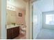 Bright bathroom featuring a vanity with dark wood cabinets, a toilet, and access to a hallway at 67 N Montoro Ln, Casa Grande, AZ 85194