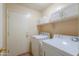 Functional laundry room with machines, storage cabinets and a door to the outside at 67 N Montoro Ln, Casa Grande, AZ 85194