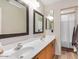 Bathroom featuring a double sink vanity, two mirrors, modern fixtures, and a shower with a white shower curtain at 9566 N 83Rd Dr, Peoria, AZ 85345