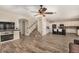 Open concept living area flows to the kitchen with bar stool seating, staircase, and fireplace at 9566 N 83Rd Dr, Peoria, AZ 85345