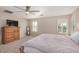 Spacious main bedroom featuring a ceiling fan, shuttered windows, and a wooden dresser with TV at 9566 N 83Rd Dr, Peoria, AZ 85345