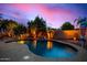 Backyard swimming pool with rock waterfall feature and lush landscaping, perfect for relaxing evenings at 9566 N 83Rd Dr, Peoria, AZ 85345