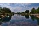 Scenic pond view reflecting the sky, with trees and landscaping adding to the tranquil community atmosphere at 10387 W Runion Dr, Peoria, AZ 85382