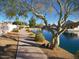 Picturesque view of paved path, landscaping, and tranquil pond surrounded by trees at 10387 W Runion Dr, Peoria, AZ 85382