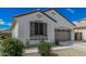 Charming home exterior with neutral stucco, green shutters, manicured bushes, and a spacious two-car garage at 14419 W El Cortez Pl, Surprise, AZ 85387