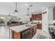 An open-concept kitchen and living area includes an island with a sink, brown cabinets, and tile floors at 14419 W El Cortez Pl, Surprise, AZ 85387