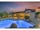 Beautifully landscaped backyard with pool, patio, and elegant lighting at sunset at 15716 W Sheridan St, Goodyear, AZ 85395