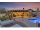 Outdoor living space with lounge chairs and meticulously landscaped lawn surrounding a pool at dusk at 15716 W Sheridan St, Goodyear, AZ 85395