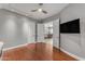 Living room with hardwood floors, TV, and open doorway to dining area at 15716 W Sheridan St, Goodyear, AZ 85395
