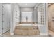 Serene main bathroom with an oval soaking tub, tile surround, and tiled walk-in shower at 15716 W Sheridan St, Goodyear, AZ 85395