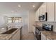 Well-lit kitchen with stainless steel appliances, white cabinets, granite countertops, and easy access to the living space at 24184 W Gibson Ln, Buckeye, AZ 85326