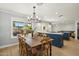 Bright dining and kitchen area with view to outside, featuring a wooden table and a stylish chandelier at 2435 E Jensen St, Mesa, AZ 85213