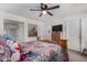 Sunlit bedroom with wooden bed frame, ceiling fan, and doorway to ensuite bath at 30517 W Lynwood St, Buckeye, AZ 85396