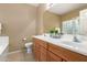 Bathroom featuring double sinks, wood cabinets, and a glass block window for natural light and privacy at 3239 S Tatum Ln, Gilbert, AZ 85297